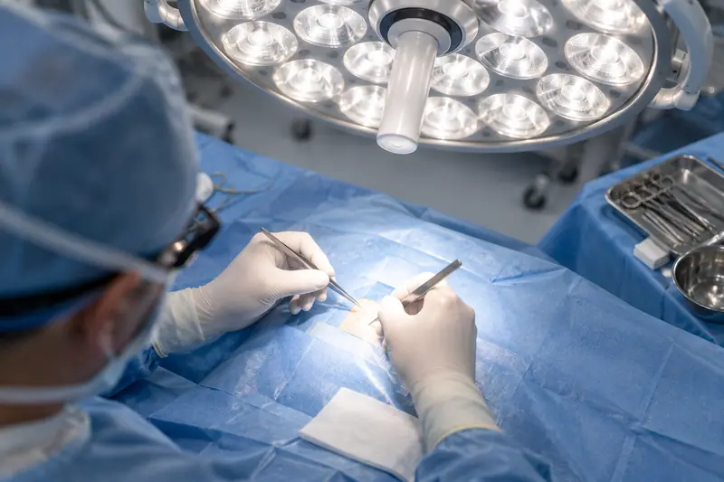Two gloved hands working under an LED surgical light dome with many small light sources and almost no shadow